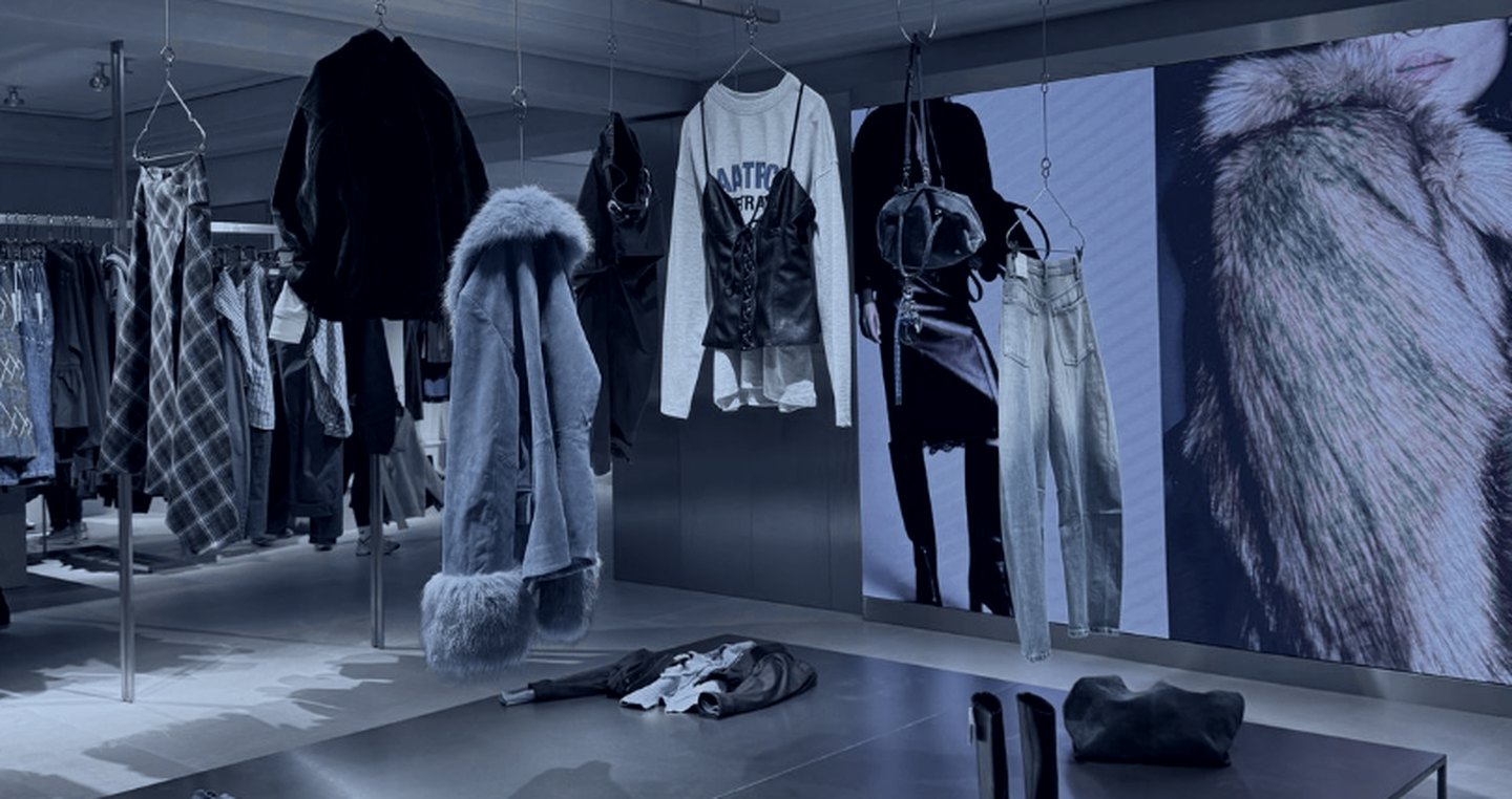 A pop up retail floor with hanging rails and a full height campaign screen, international fashion pop ups by DE Agency