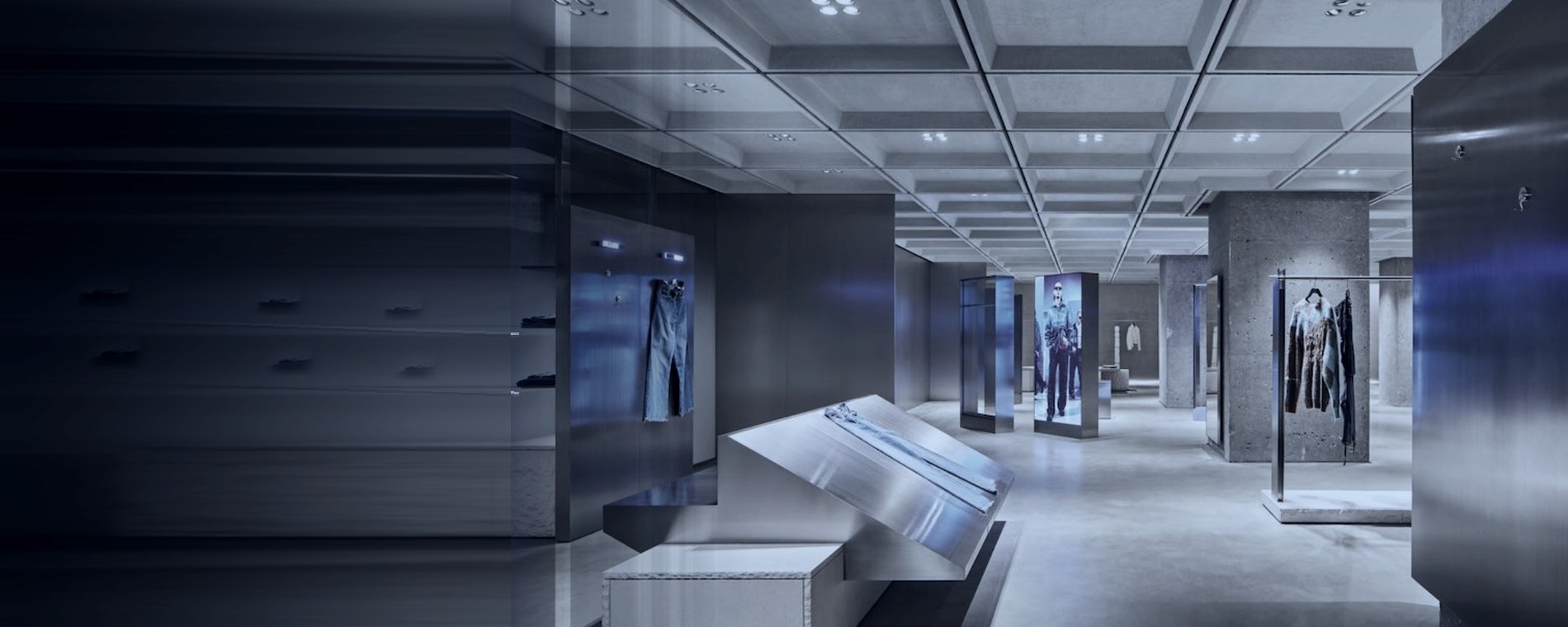 A concrete and brushed steel retail floor with lit display bays, fashion operations and distribution