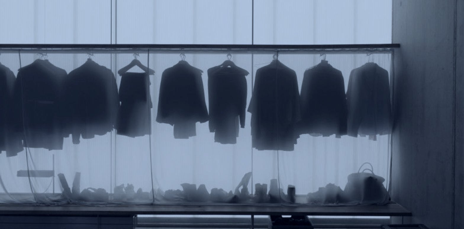 A rail of tailoring seen through frosted glass, fashion showroom and buyer outreach by DE Agency